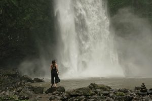 Woman pauses at foot of waterfall by daria lisovtsova - Ubuntu Budgie 26.04 Wallpapers - Official Indigo Collection